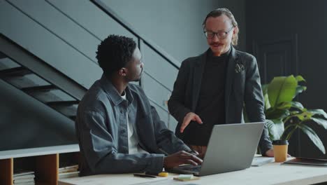 businessman explaining data on laptop to colleague in office