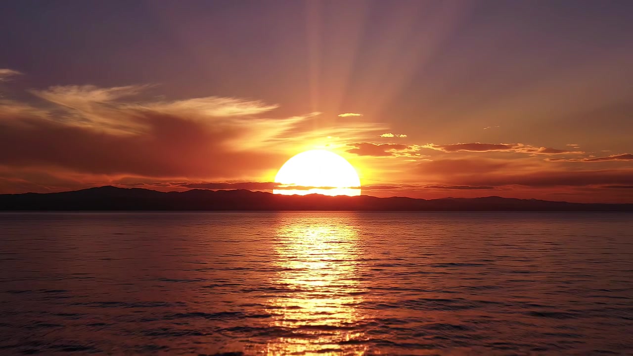 Wunderschöner Sonnenuntergang über dem Meer mit Bergen und goldenen Sonnenstrahlen
