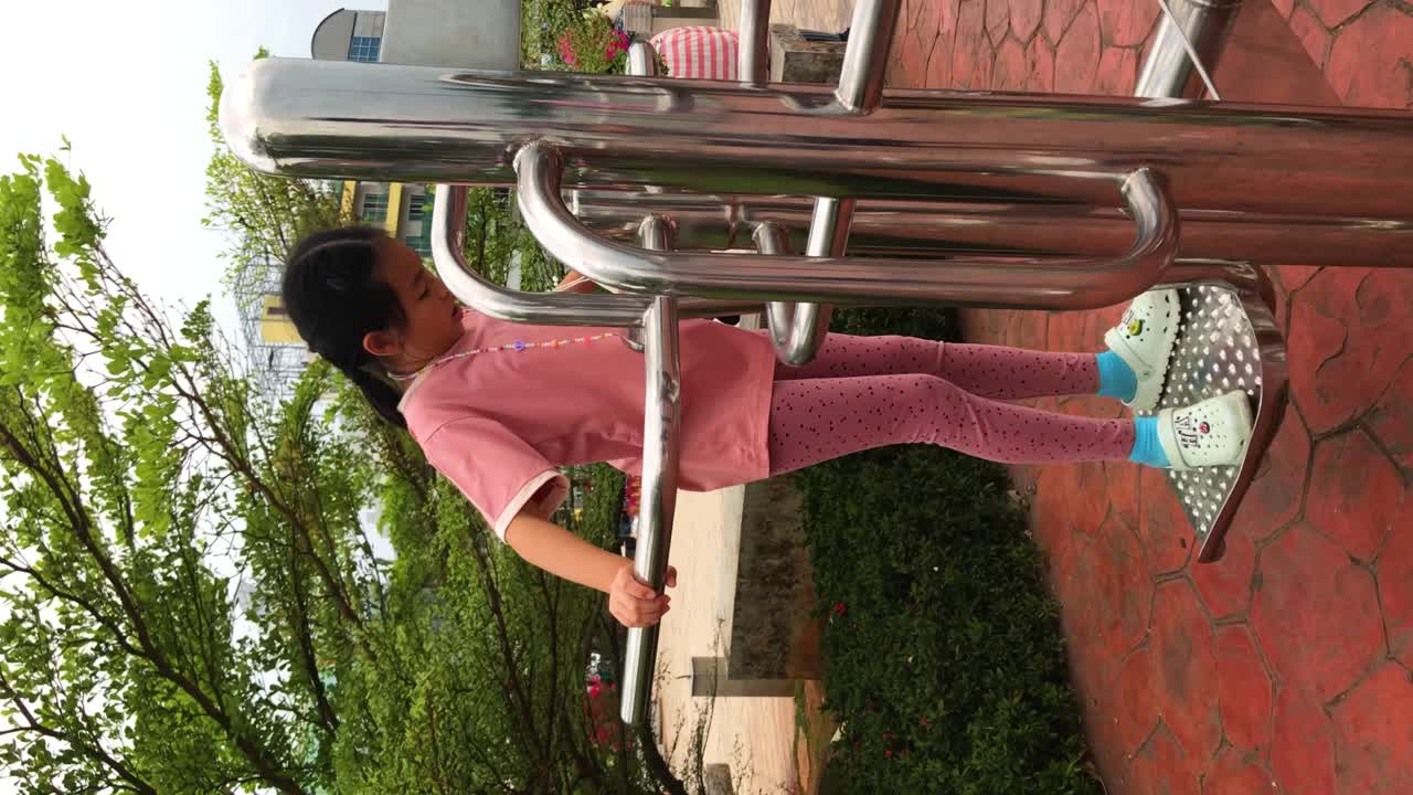 niña asiática jugando con equipos de ejercicio en un parque público en tailandia, imágenes verticales