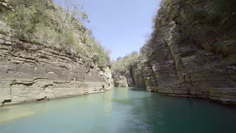 Barco-Navegando-A-Través-De-Cañones-De-Rocas-Sedimentarias,-Vegetación-Y-Agua-Verde