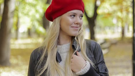 mujer en boina roja caminando en el parque