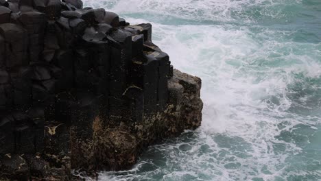 dynamic ocean waves hitting a rugged basalt cliff