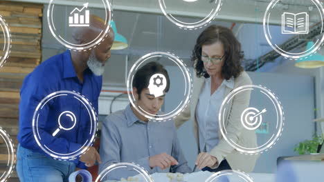 Animation of business icons over diverse business people discussing work