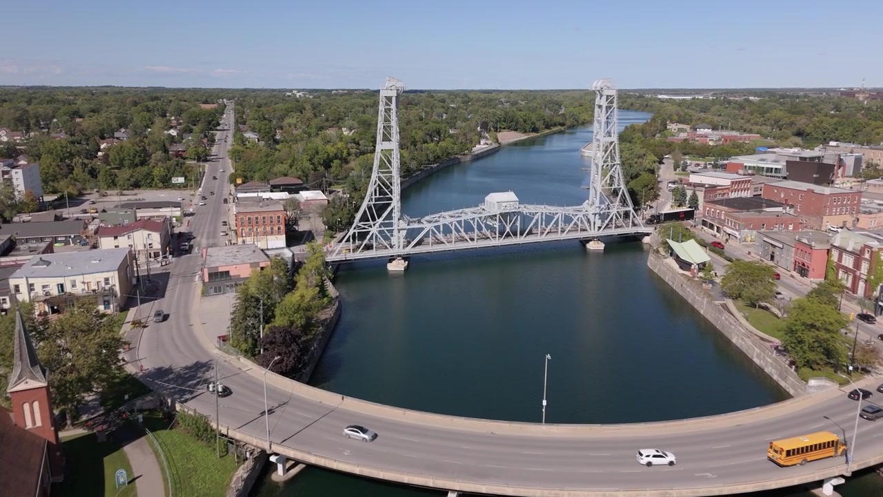Drone che vola verso un ponte mobile sul canale con traffico che scorre intorno e lo skyline della città in lontananza