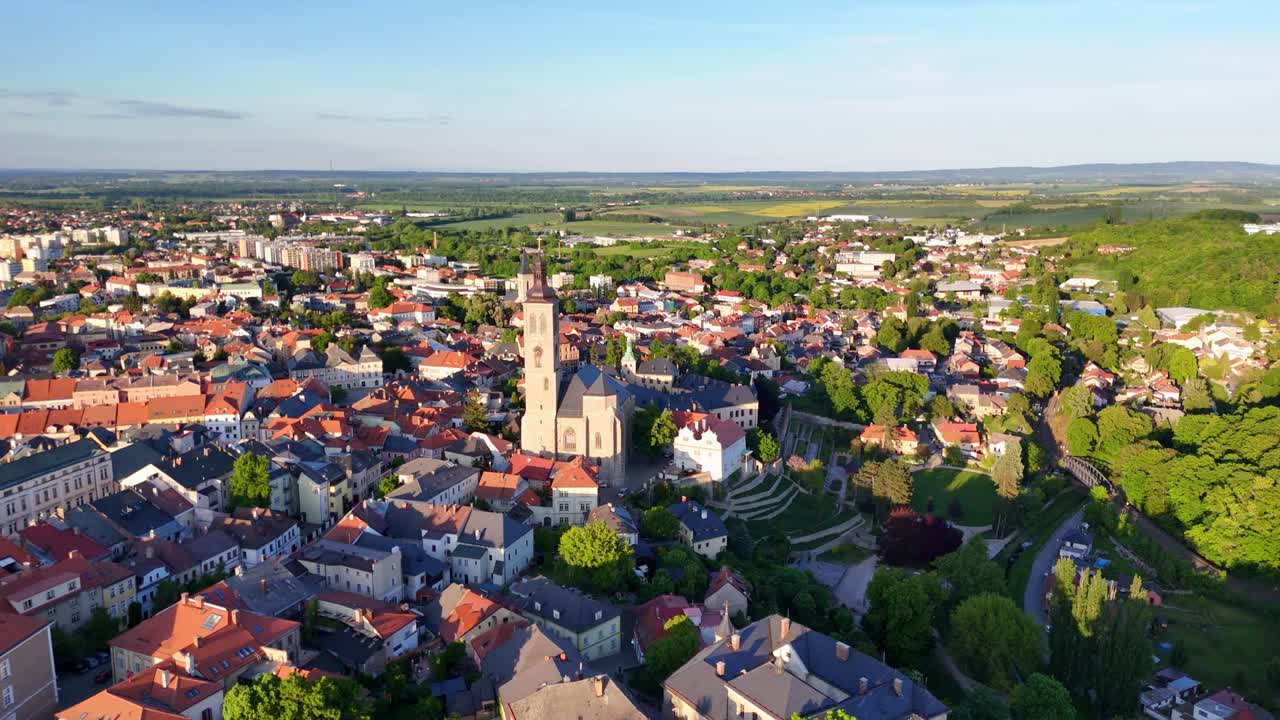 Sweeping aerial of Kutná Hora with St. James Church and surrounding medieval town in golden afternoon light. Czech Republic