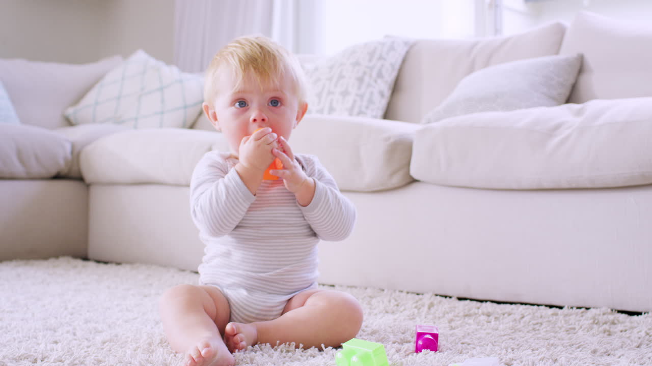 ⁇ 색 유아 소년이 바닥에 앉아서 놀고 있다.