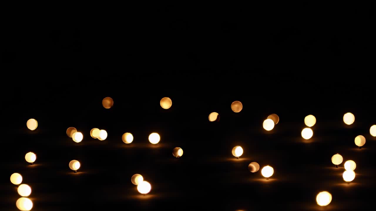 Luci bokeh sparse su uno sfondo scuro, catturate da una angolazione bassa
