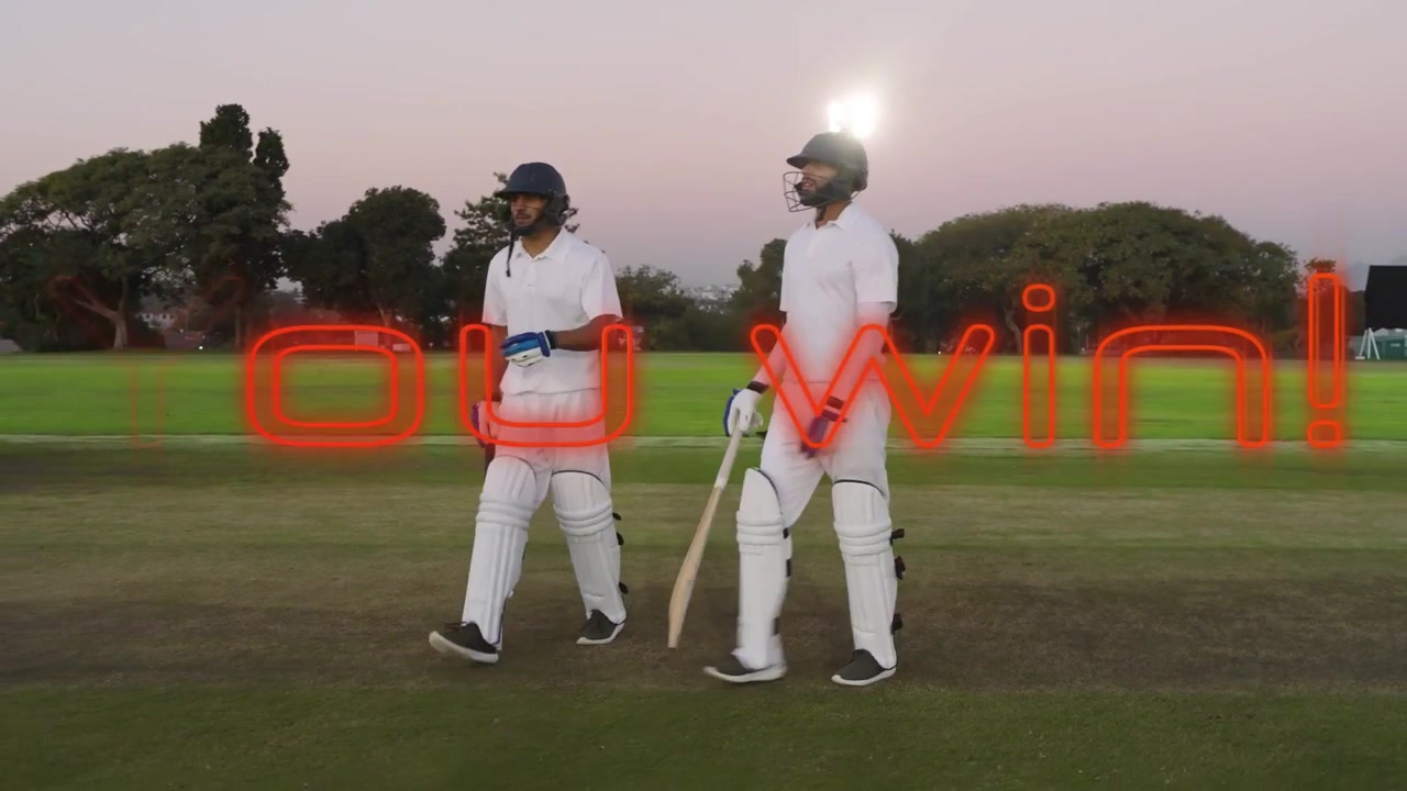 To gærdespillere slår handskerne sammen, går og fejrer sejr på en cricketbane med et rødt neon "Du vandt!"-overlay