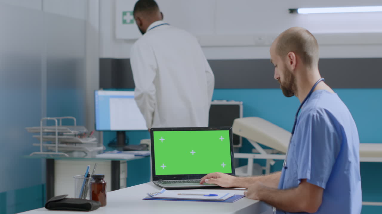 Doctor using laptop with green screen in clinic
