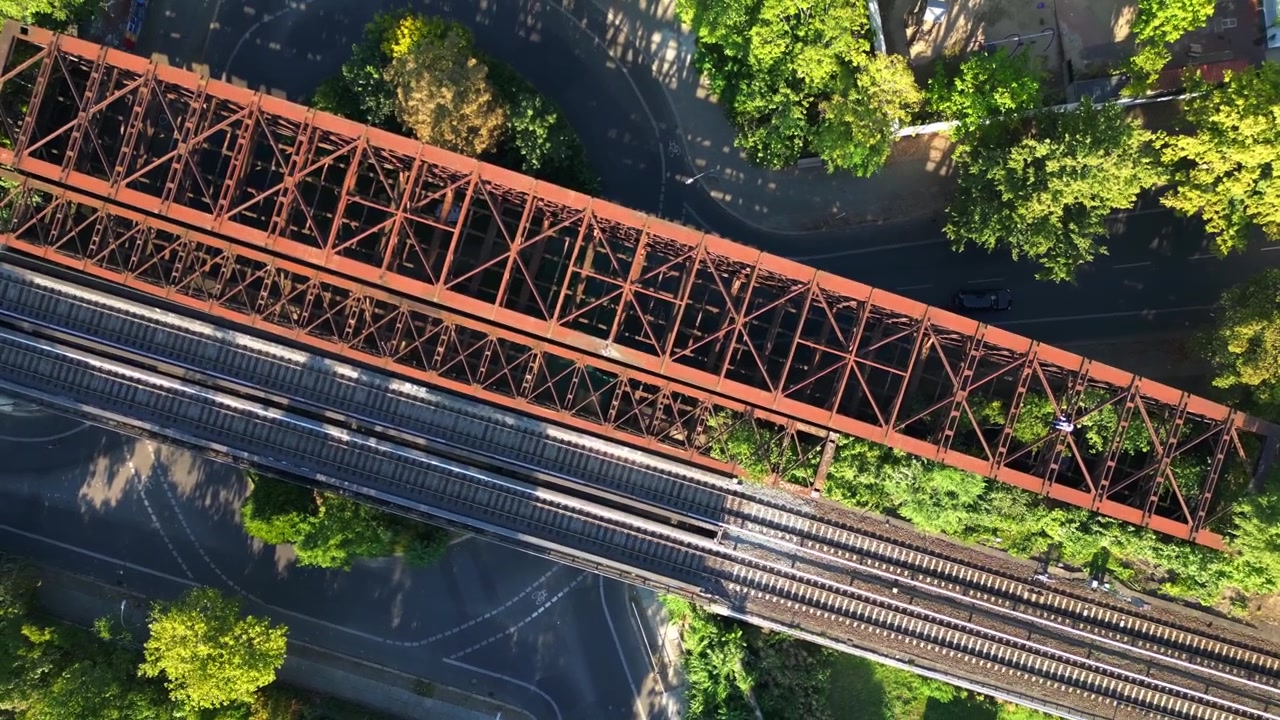 Ponte ferroviario arrugginito che passa sopra i binari del treno in un contesto urbano lussureggiante e verde a Berlino, Germania, infrastruttura di trasporto. Perfetta vista aerea ripresa da drone con telecamera puntata verso il basso.