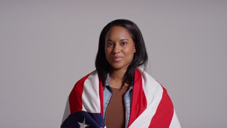 studio portrait shot of woman wrapped in american flag celebrating 4th july independence day 9