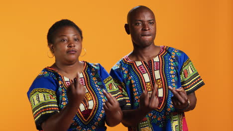 rude ethnic couple showing middle finger in studio