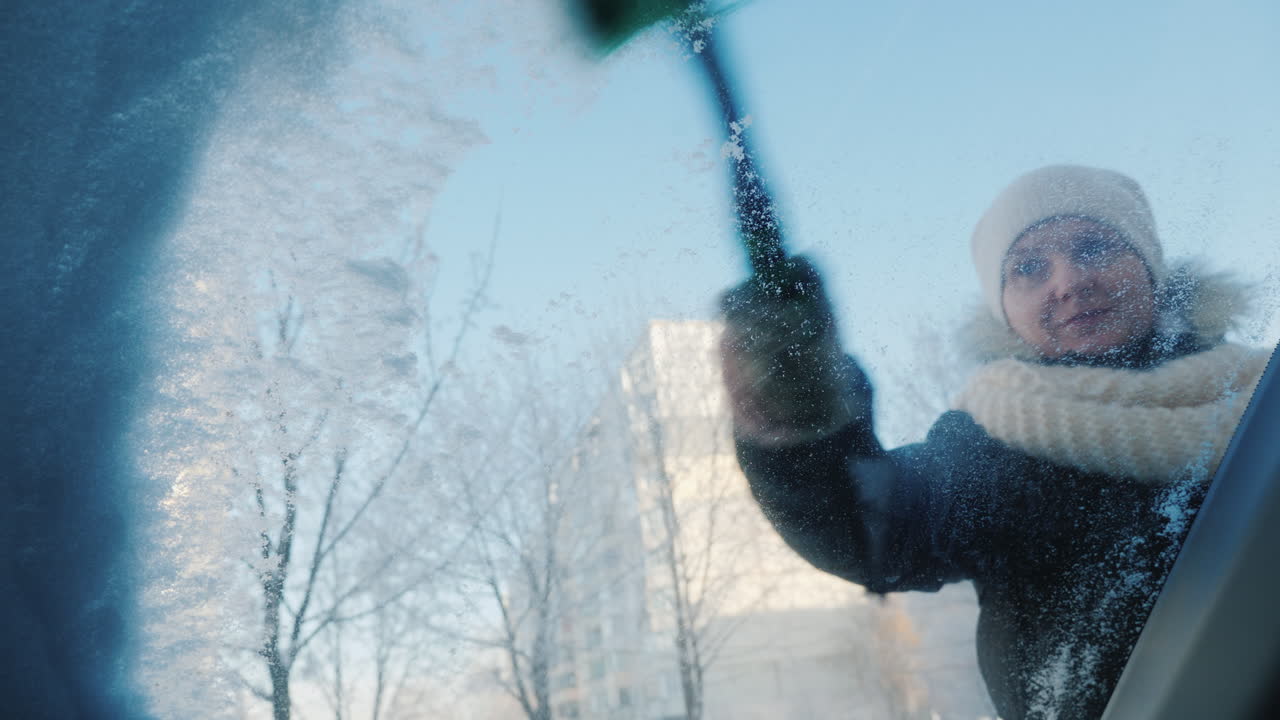 여자가 차에서 눈을 치우고 있다