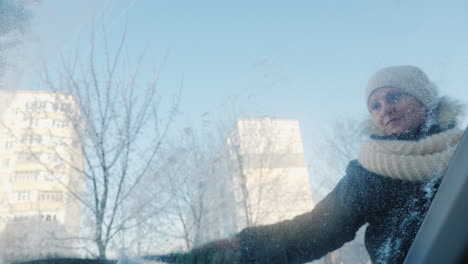 una mujer quita la nieve de su coche