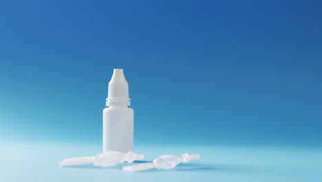 video of saline caplets and dropper bottle on blue background with copy space