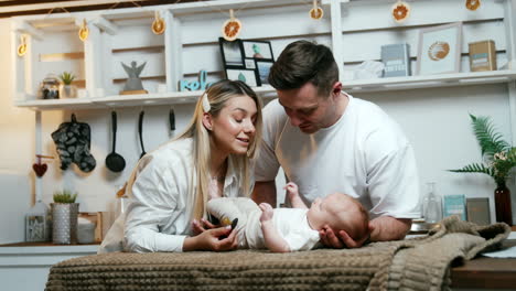 young parents stand over their newborn child lying on the plaid. couple enjoying time with newborn baby. mom is holding a pacifier.