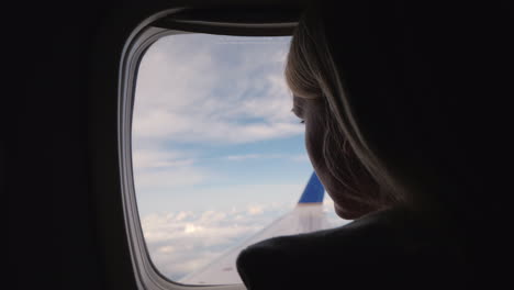 mujer volando en un avión mirando por la ventana