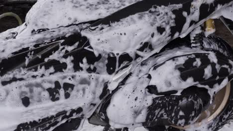black sleek motorbike, washing chores, soapy suds, close-up view