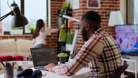 african american software developer works on programming code on a laptop