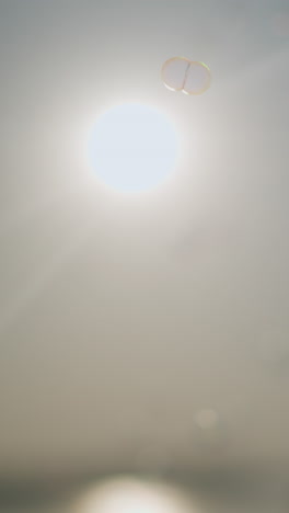 una escena suave y etérea de burbujas flotando suavemente en el aire bajo un sol brillante. la luz del sol crea una atmósfera serena y onírica
