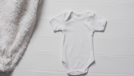 video of white baby grow and white furry rug with copy space on white background