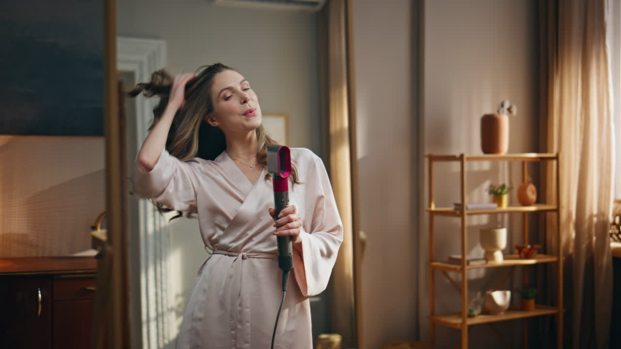 Woman Styling Hair with Hair Dryer in Bathroom