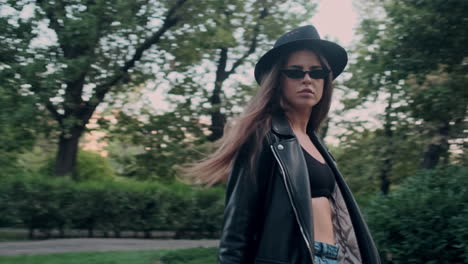 joven modelo con gafas de sol y caminando en el jardín