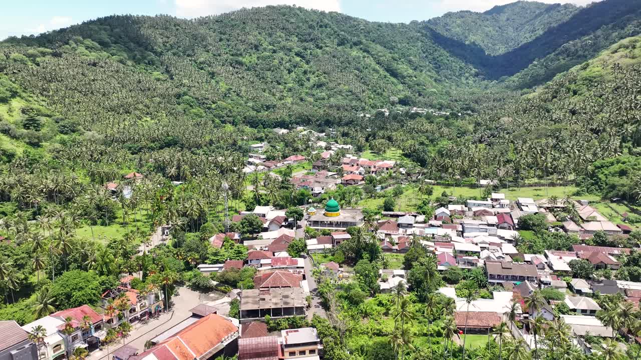 vista aérea de una ciudad rodeada de montañas con árboles verdes en la isla de lombok, indonesia.