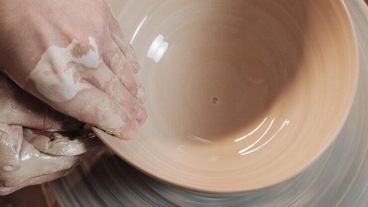 Hands shaping a bowl on a pottery wheel