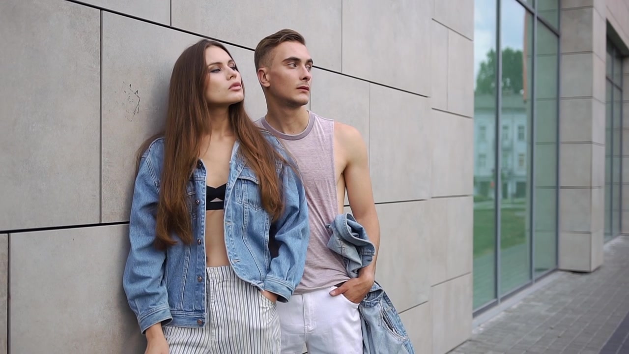 Young Couple Posing Against Modern Building Wall