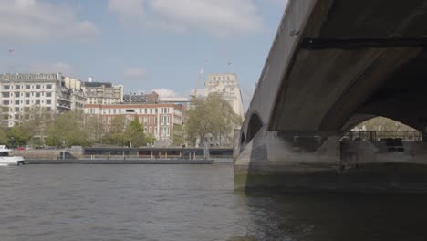 Blick-Vom-Boot-Auf-Die-Themse,-Die-Unter-Der-Waterloo-Brücke-Hindurchfährt-Und-Die-Skyline-Der-Uferböschung-Zeigt