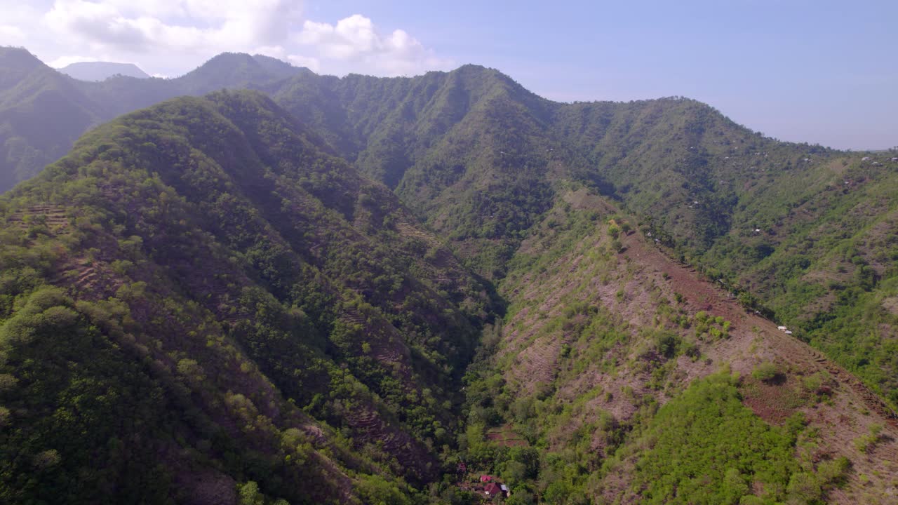 Ripide montagne verdi dominano il paesaggio naturale attorno ad Amed, Bali, con un crinale montuoso in prospettiva aerea.