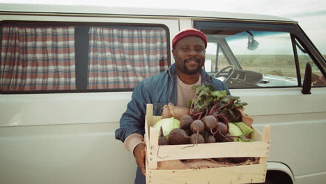 retrato de un feliz agricultor afroamericano con una caja de verduras