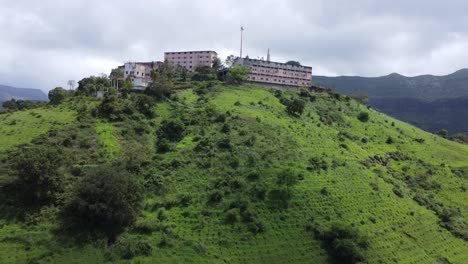 Aerial-view-of-Nil-Parvat-sacred-temple-on-the-edges-of-Brahmagiri-hills-surrounded-by-lush-greenery-in-Trimbakeshwar-town,-Nashik,-Maharashtra,-India