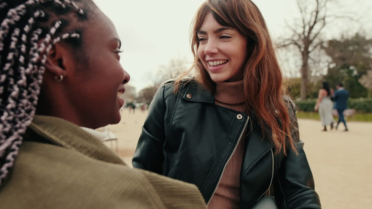 Two Young Diverse Women Talking and Smiling in a Park