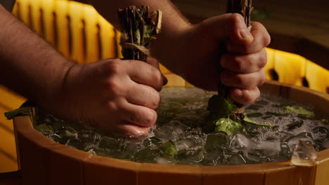 preparing birch brooms in an ice bath for a traditional russian banya session