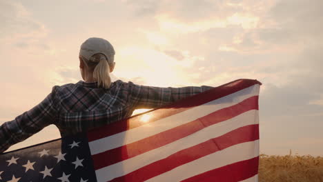 A-Man-With-An-American-Flag-In-His-Hands-Stands-On-A-Field-Of-Ripe-Wheat