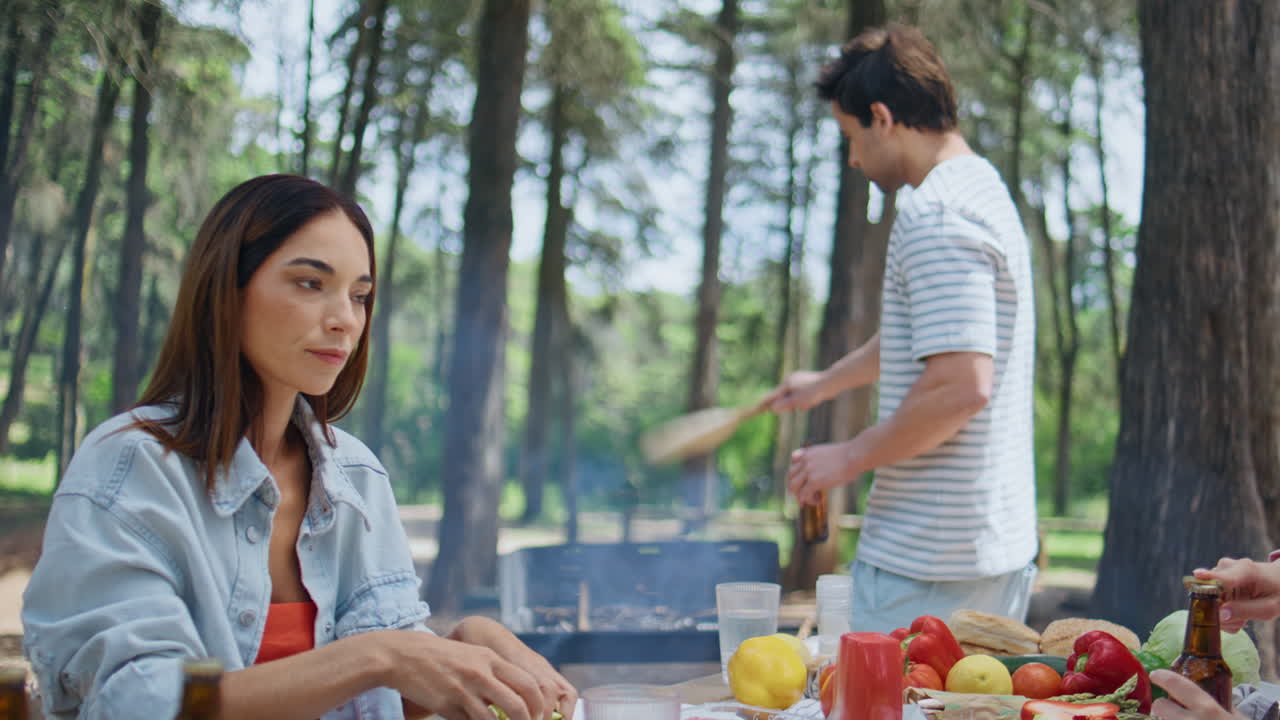 a woman preparing food at picnic in forest closeup. Man blowing fire