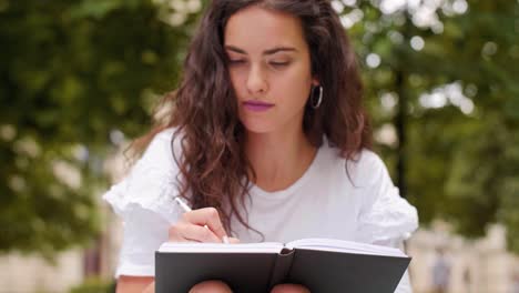 una chica escribiendo un diario en el parque.