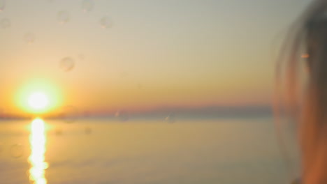 girl blowing bubbles at sunset