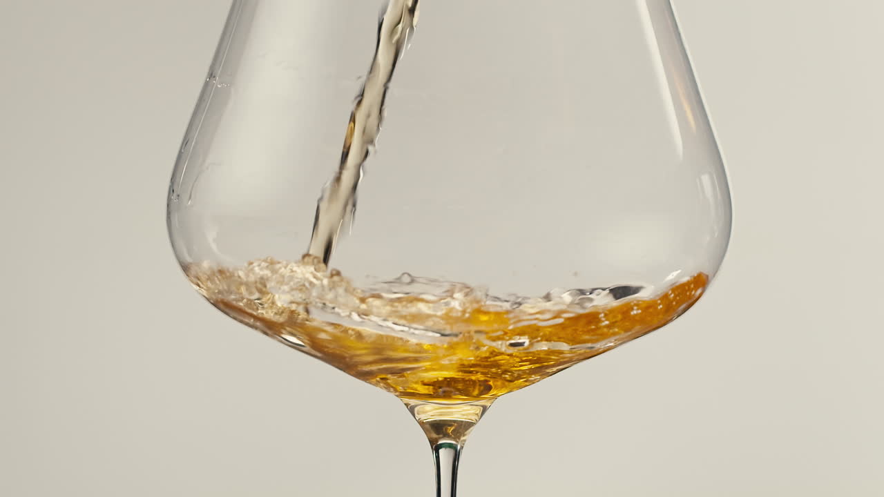 Orange or white wine bottle and glass against a sunset in a peaceful vineyard, pouring of ecological natural wine.