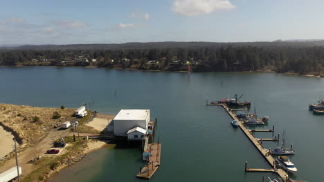 Aerial-circle-over-white-building-at-Charleston-Marina-complex-port-of-Coos-bay,-Oregon