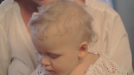 a woman holding a cute baby girl who is playing with a wooden pin