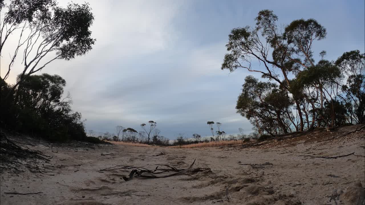 Toma terrestre de un lapso de tiempo de un sendero arenoso y nubes al atardecer, Australia Occidental