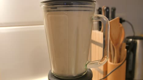 vista de la mezcla casera de avena y leche moliendo en una licuadora haciendo leche de avena en la cocina