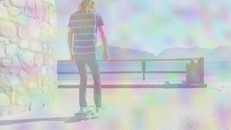 Adult male pushing off on skateboard riding coastal path for sports, prism haze guiding to railing