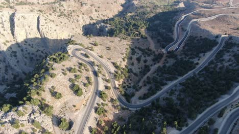 vista de avión no tripulado en grecia volando sobre una montaña marrón y verde con carretera de serpiente y mar en el horizonte en un día soleado