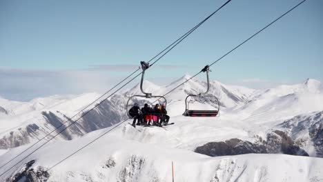 ski lift full of people going uphill the mountain during winter