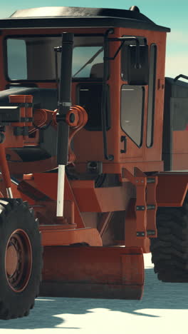 close-up of an orange motor grader in the snow