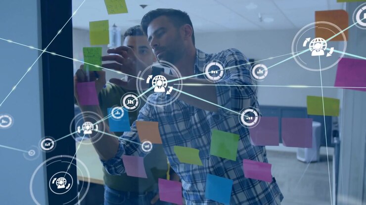 Two men marking glass, moving notes and initiating network overlay for business planning